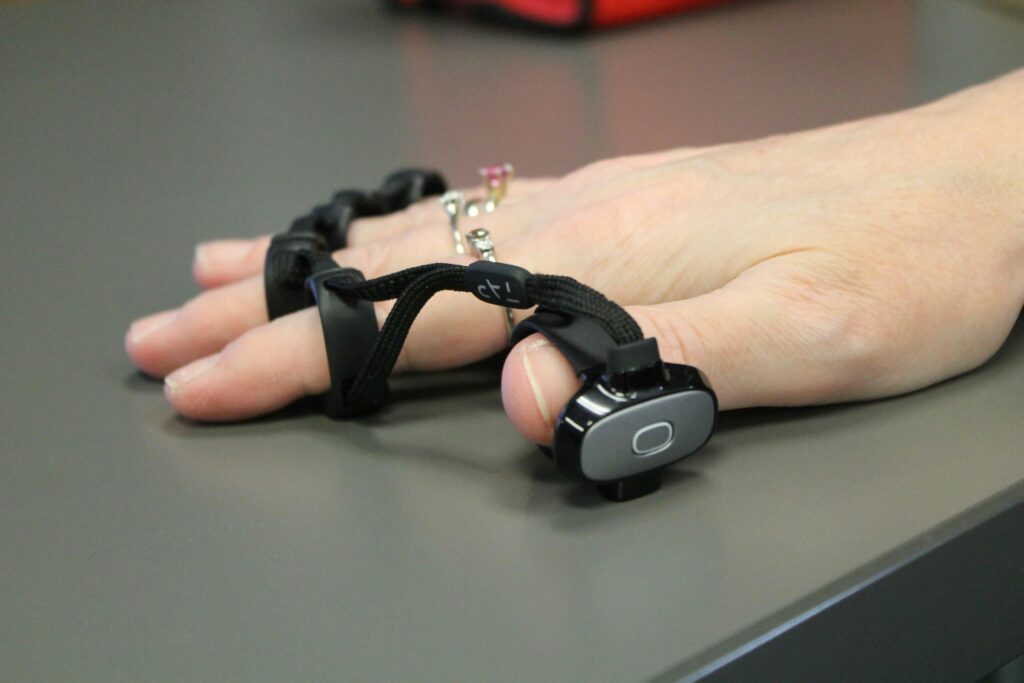 A person's hand flat on a table with an accessible decide on each of the fingers for a virtual keyboard.