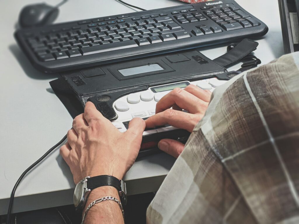 Person's hands on desk pressing accessible keyboard buttons